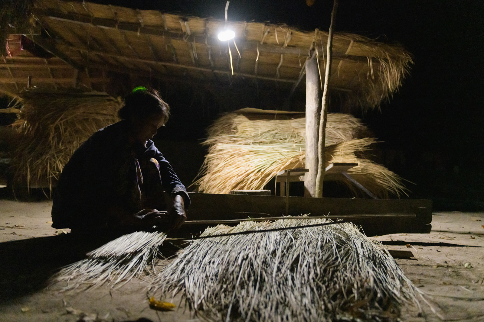 Photo: A woman who works at night (weaving a roof)