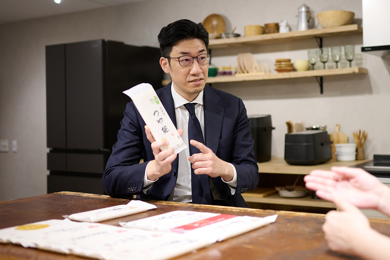 Photo: Ohmiya holding a small-portion pack of brand-name rice from collaboration partner Kuriya