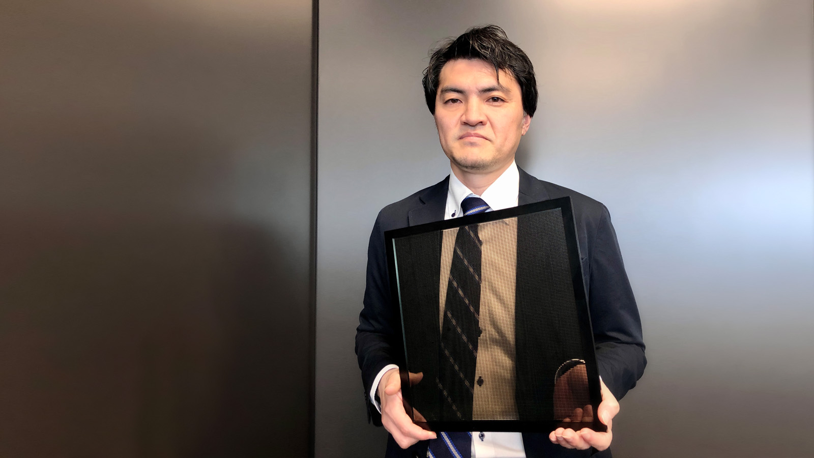 Photo: Yukihiro Kaneko of the Applied Materials Technology Center, Technology Division, Panasonic Holdings Corporation shows off a semitransparent perovskite solar module