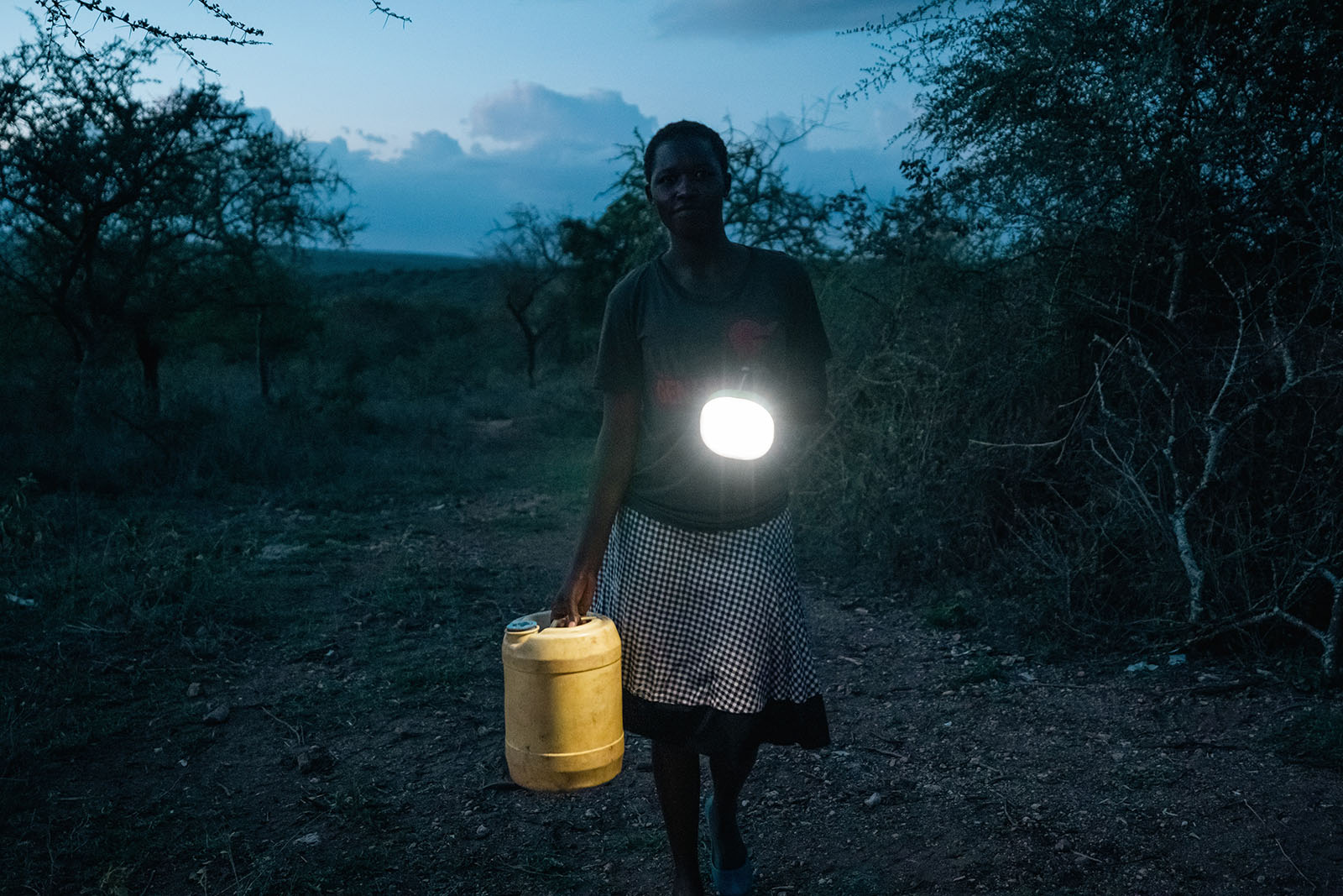 Photo: A girl fetches water from the river by the light of a solar lantern