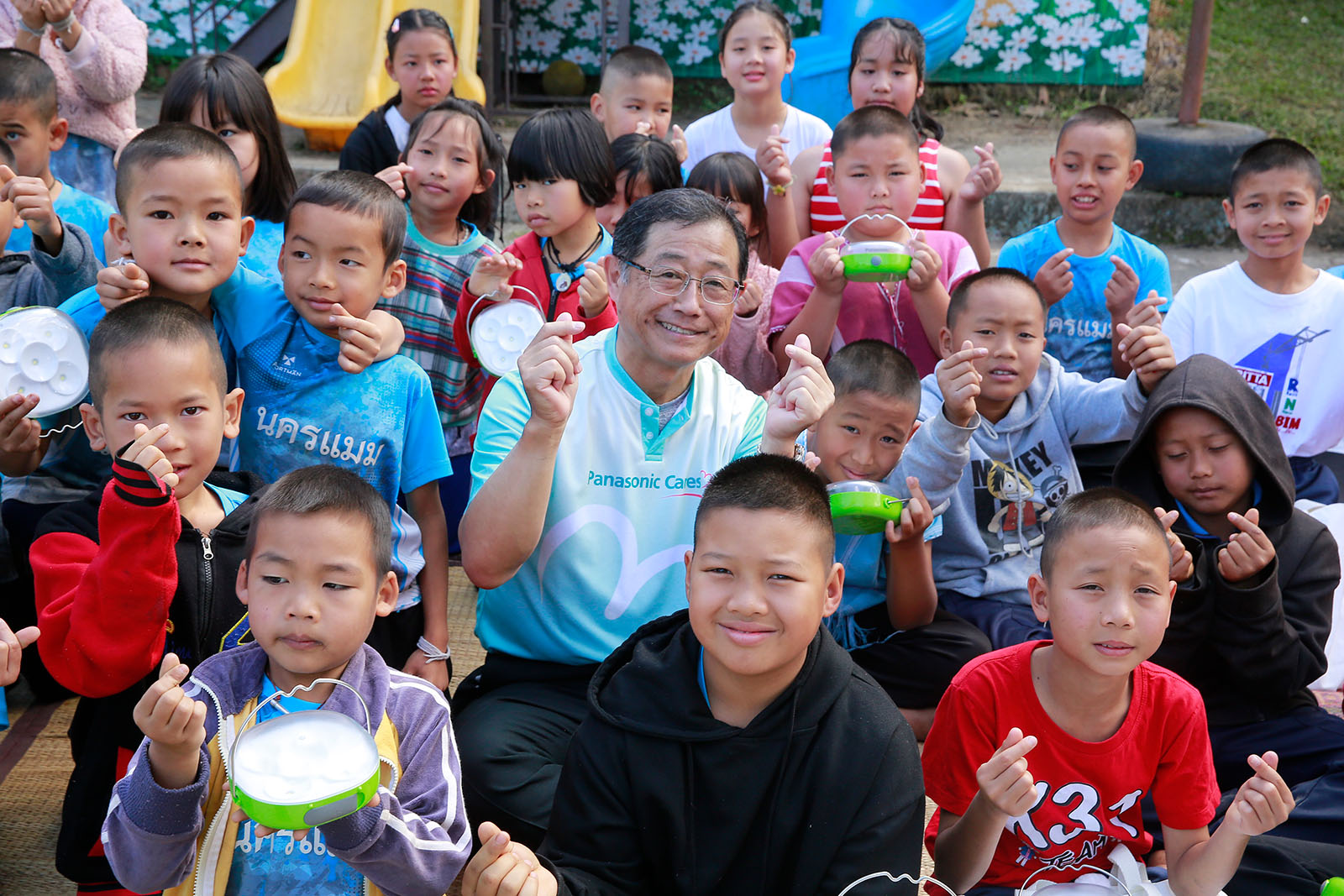 Children and a Panasonic Group representative at a solar lantern donation event in Thailand.